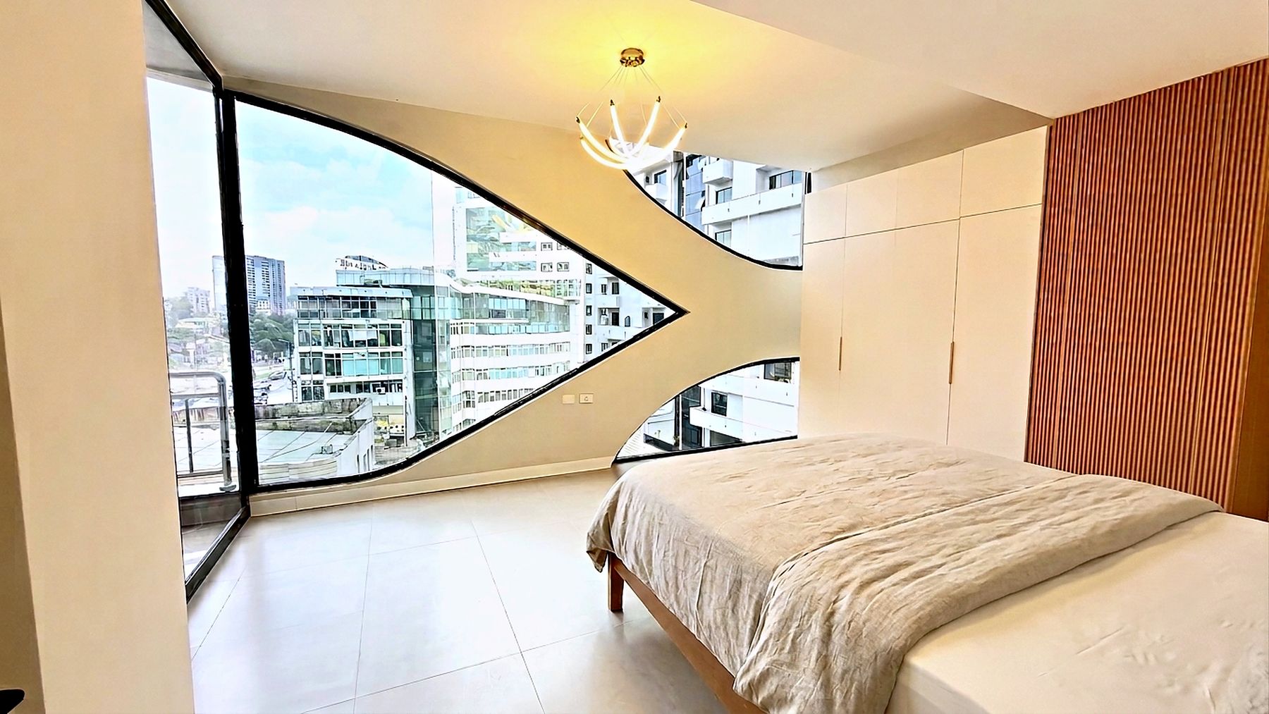 Bedroom with a leaf shaped window framing the Bole skyline, matching the openings cast into the facade