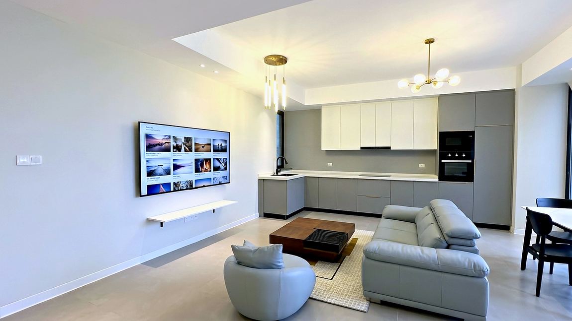 Living room with a wall mounted television facing the kitchen